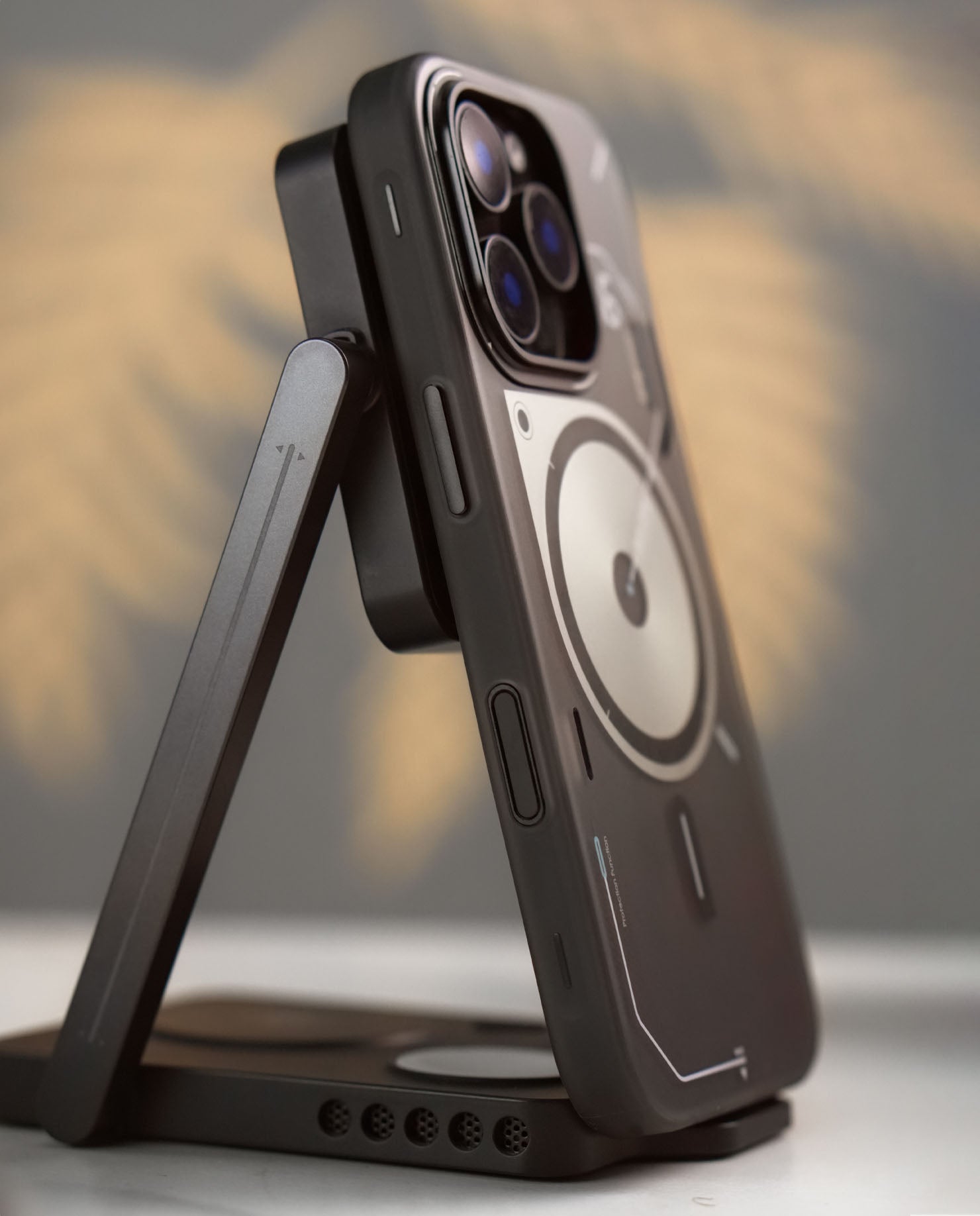 高品質な金属ボタンとカメラリングを備えた A16 フロステッド iPhone ケースをスタンドに立て、側面のディテールを強調したイメージ