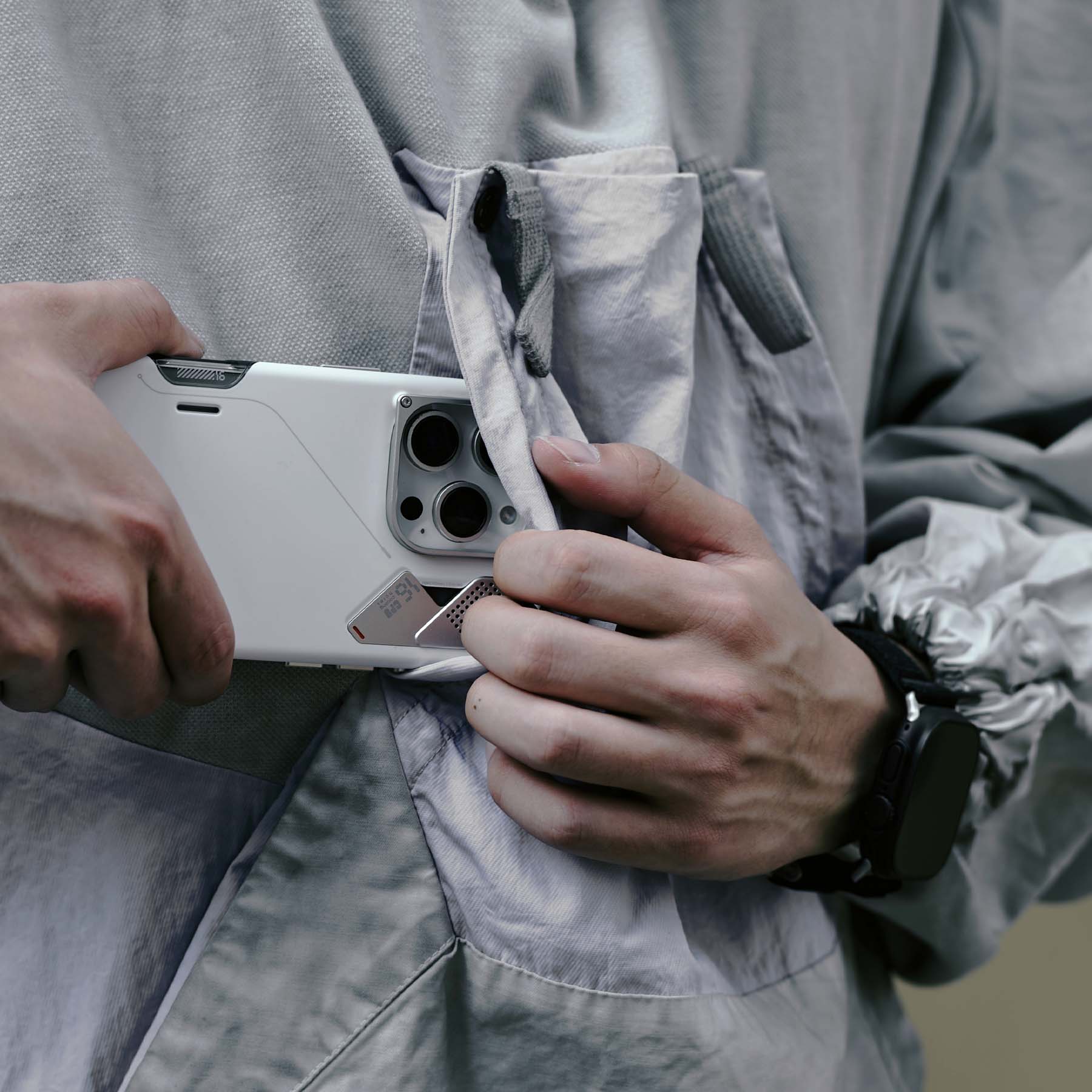 A16 スリム耐衝撃ケースを装着した iPhone を、ジャケットのポケットから出し入れしている様子