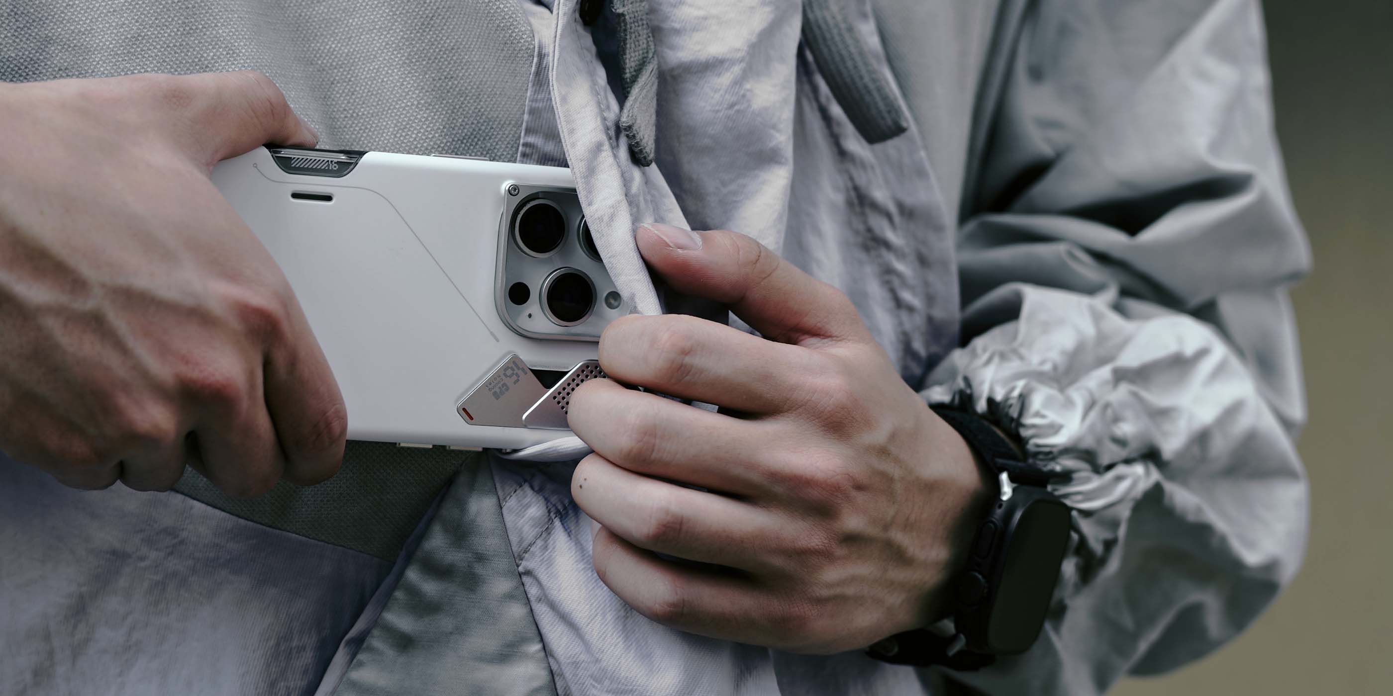 A16 スリム耐衝撃ケースを装着した iPhone を、ジャケットのポケットから出し入れしている様子