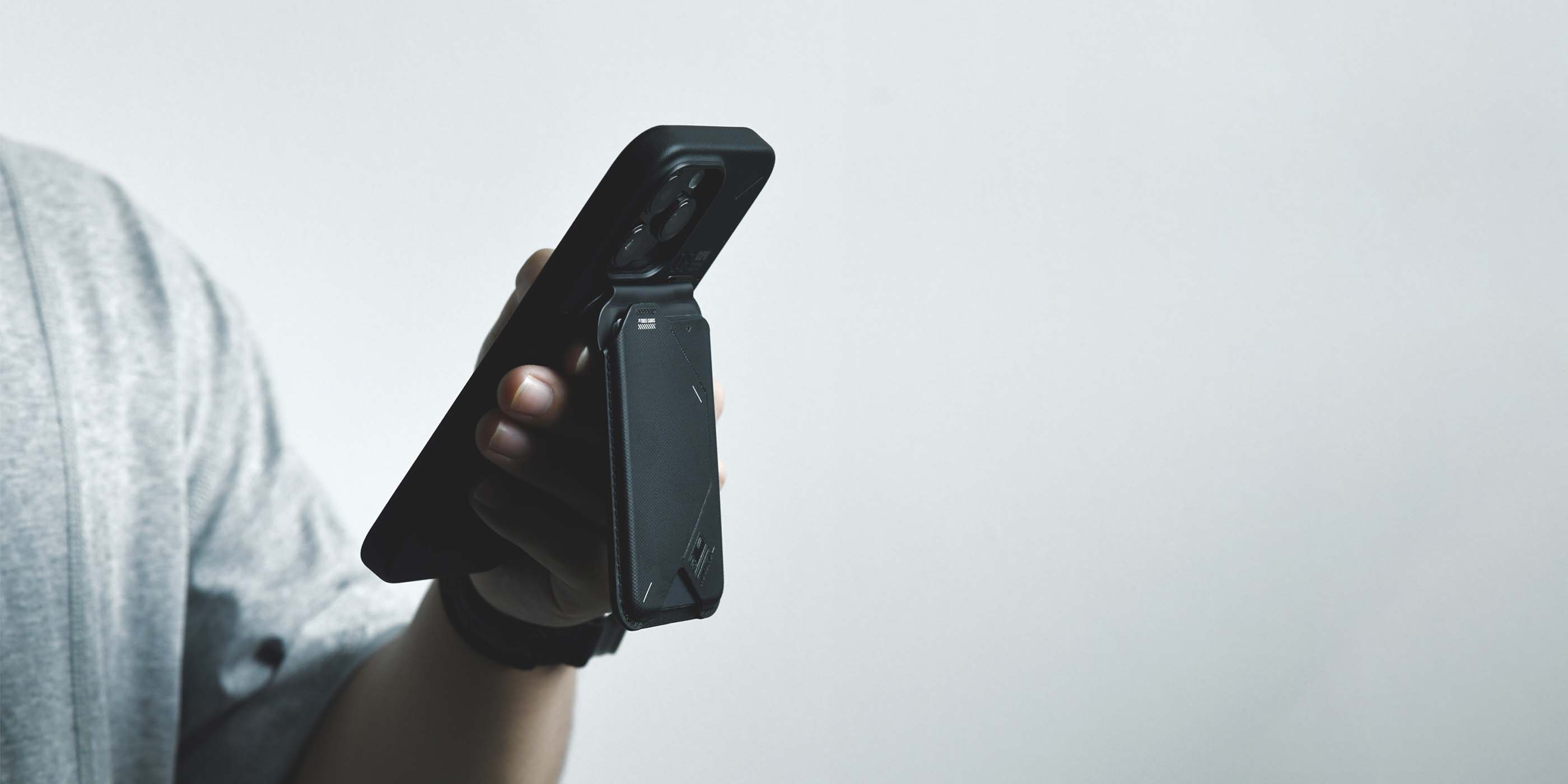二つ折りでもスリムな G02 マグネティックフリップウォレットを装着したスマートフォンを、片手で握って操作している様子