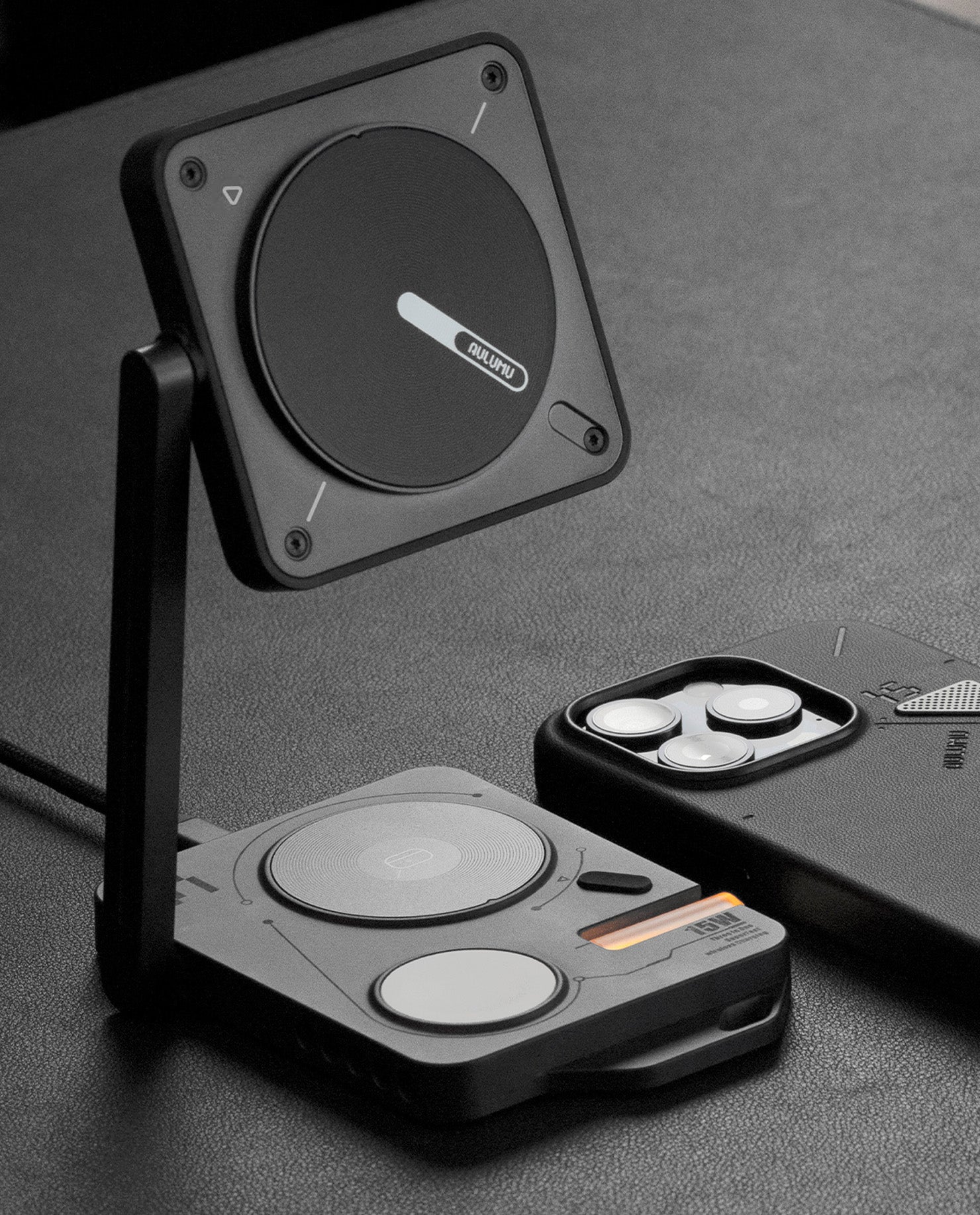 MagSafe 充電パッドを縦型スタンドとして立て、iPhone 用ケースと共に配置した AULUMU 4-in-1 充電ステーション