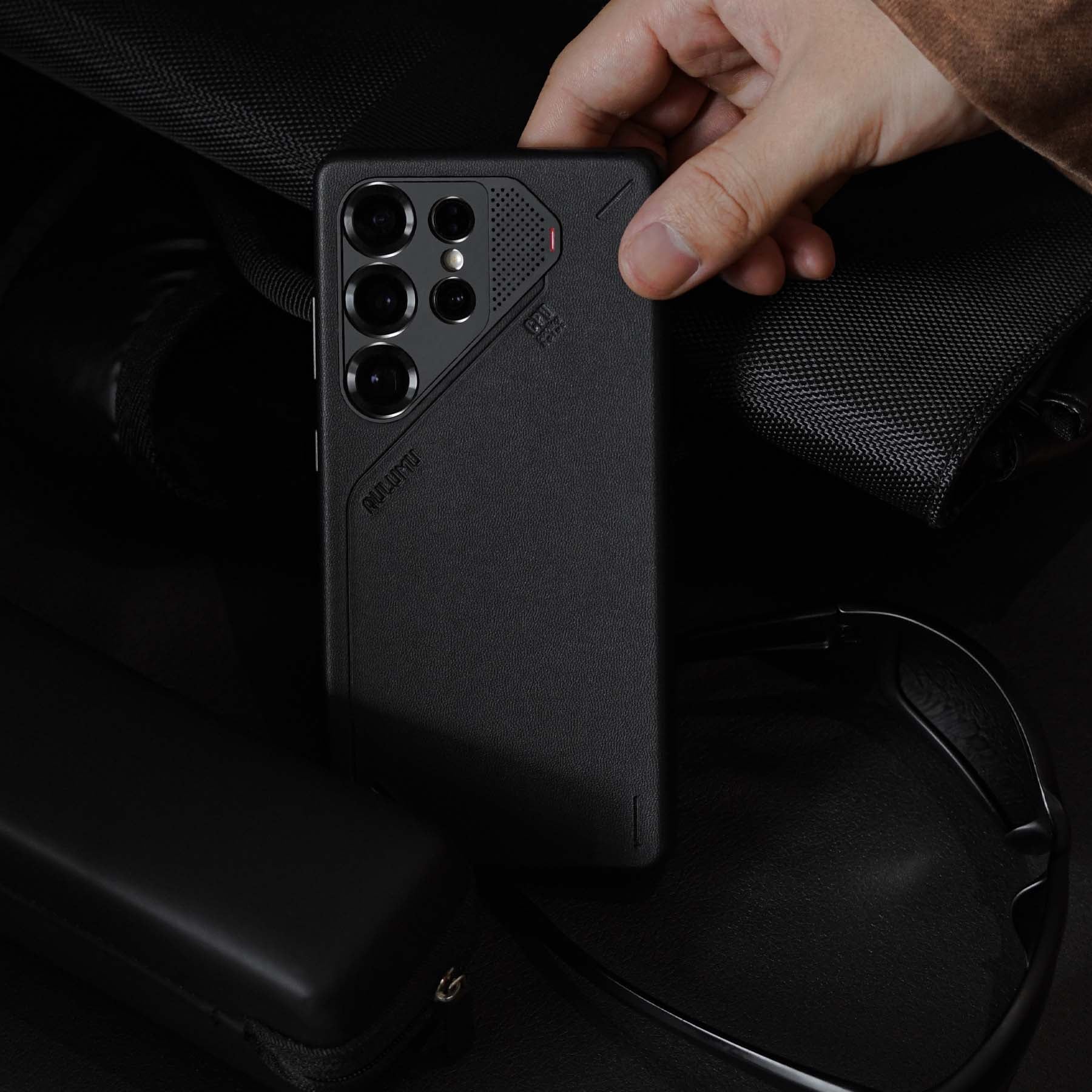 aulumu S25 Vegan Leather Caseを装着したGalaxy S25 Ultraをバッグから取り出すシーン ブラックのヴィーガンレザーとミニマルデザインが際立つライフスタイルショット