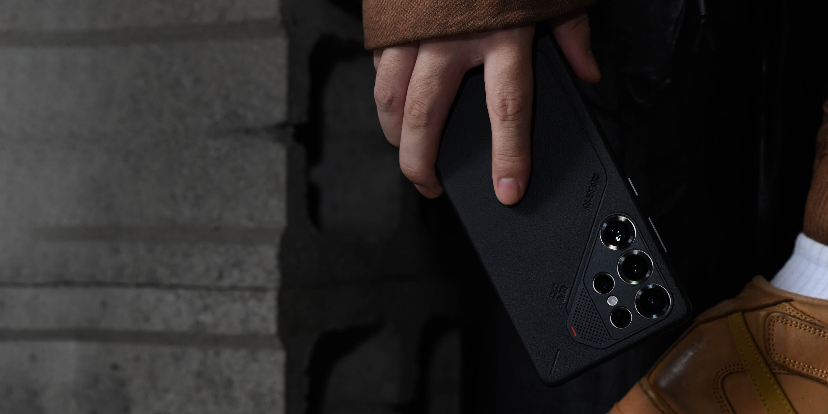 aulumu S25 Vegan Leather Caseを装着したGalaxy S25 Ultraを手に持つライフスタイルショット アルミニウム合金カメラリングがレンズ全体を保護する様子